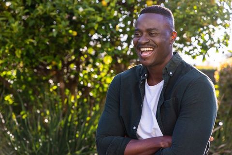 African american man laughing in sunlit garden casual portrait with bokeh background