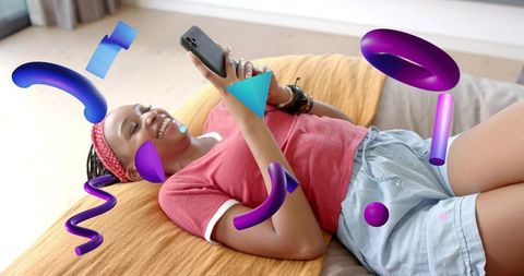 Smiling woman lounging on bed scrolling phone surrounded by vibrant 3d purple graphics