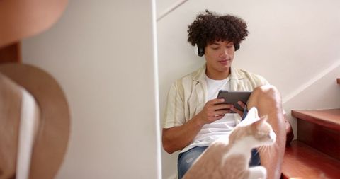 Man Sitting Casually on Stairs with Tablet and Headphones