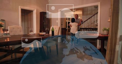 Mature couple dancing in cozy candlelit dining room with wine glasses and warm lighting