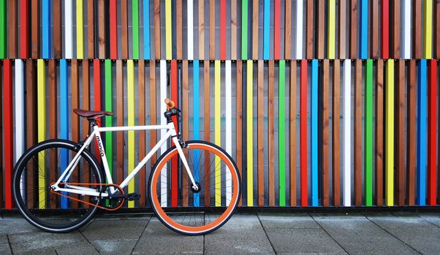 Bicycle leaning against colorful striped wall in urban setting. Perfect for urban lifestyle, transportation, and modern architecture themes. Use for advertising, city cycling promotions, and artistic backgrounds.