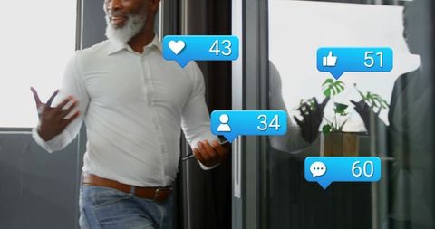 Businessman walking through office corridor using smartphone while receiving social media alerts