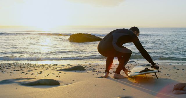 Preparing for surf at sunrise, man in wetsuit with surfboard on beach - Download Free Stock Images Pikwizard.com