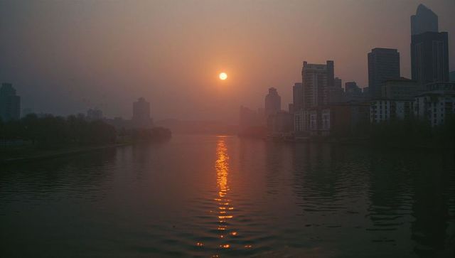 Cityscape tranquility with sunrise reflection on serene river