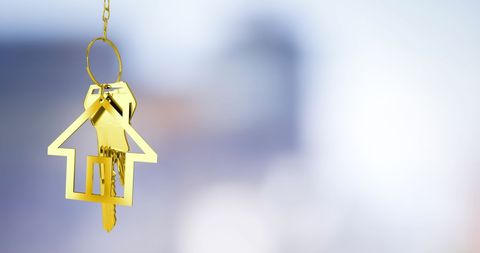 Golden House-Shaped Keychain with Blurred Urban Background