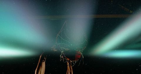 Muscular Arms Pulling Rim During Powerful Dunk Under Teal Arena Lights and Dramatic Flare
