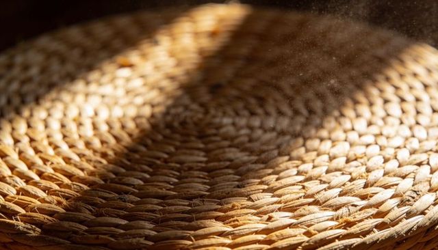Sunlit braided seagrass placemat with dust motes and warm woven texture rustic boho decor