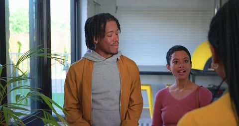 Young diverse friends chatting in bright coworking lounge with plants and modern decor