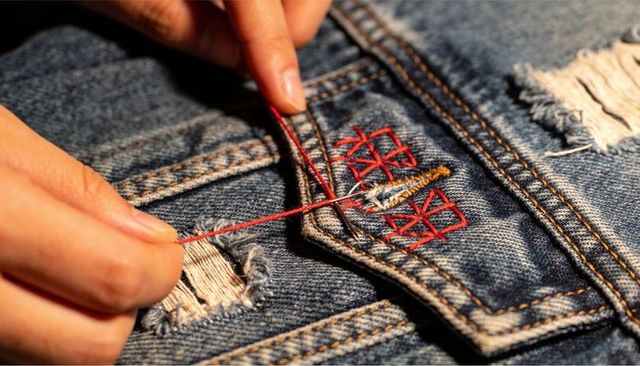 Hand Repairing Frayed Denim Pocket with Red Thread Close-up Sewing and Embroidery