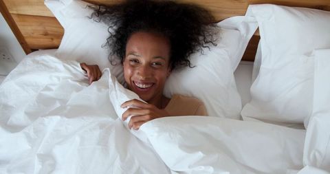 Smiling african american woman relaxing in cozy bed
