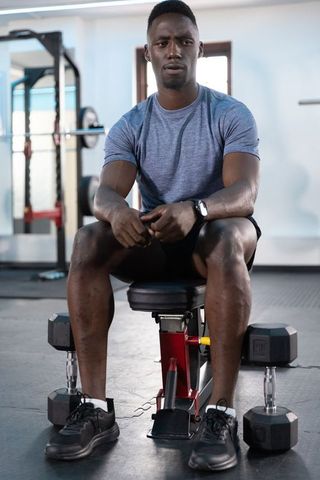 African american man resting between sets on adjustable bench with dumbbells