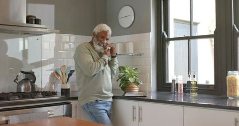 Senior man talking on smartphone in modern kitchen setting