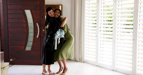 Graduate Embracing Joyful Moment in Cap and Gown at Home