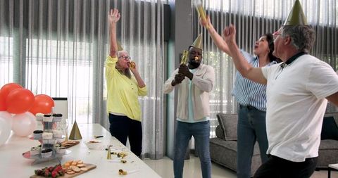 Diverse colleagues celebrating office party with dance and confetti