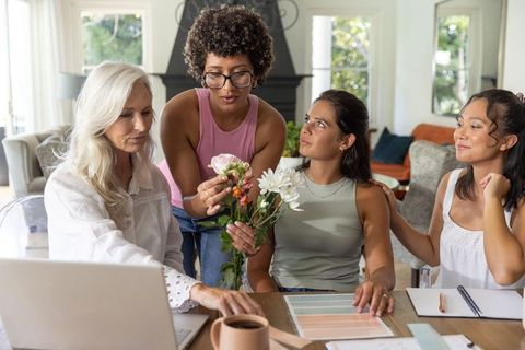 Multigenerational women collaborating on floral mood board, color swatches in sunlit living room