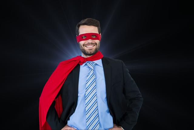 Businessman wearing superhero costume with red cape, standing confidently with hands on hips and grinning. This visual can represent concepts related to leadership, confidence, creativity, motivation, and self-empowerment in business settings. Suitable for motivational posters, corporate presentations, leadership training materials, and creative marketing campaigns.