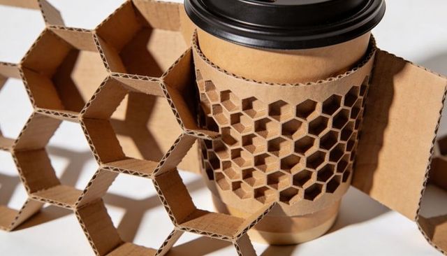 Honeycomb cardboard coffee sleeve on to-go cup casting hexagonal shadows and texture