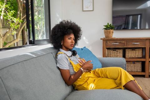 Woman in Yellow Overalls Relaxing with Headphones at Home