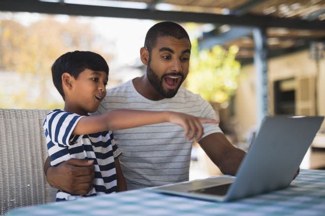 Shocked young man with his son looking at laptop on table