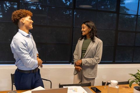 Diverse colleagues discussing charts at conference table during evening business meeting