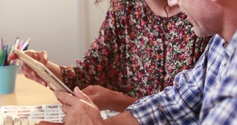 Middle-aged professionals collaborating with tablet in casual setting