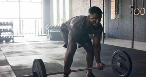 Focused Man Performing Barbell Deadlift in Modern Gym