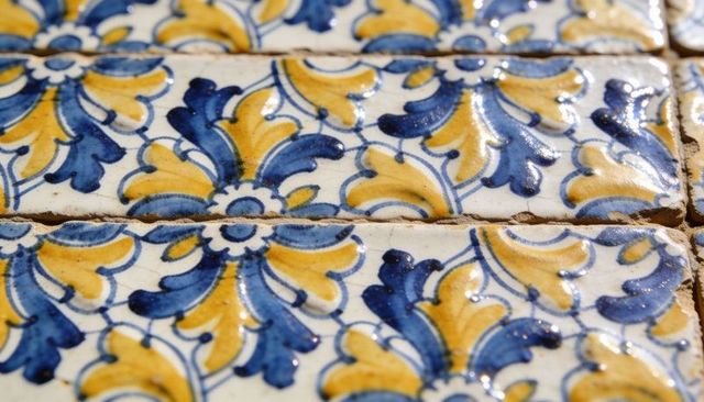 Closeup blue mustard ceramic tile panel with ornamental arabesque motif, glazed patina
