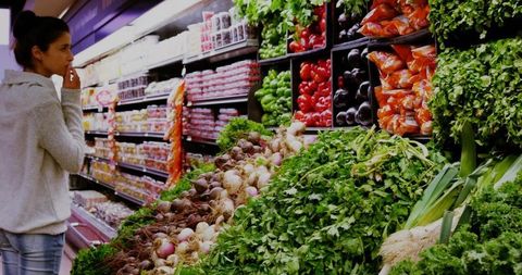 Woman Choosing Fresh Vegetables in Supermarket Produce Aisle