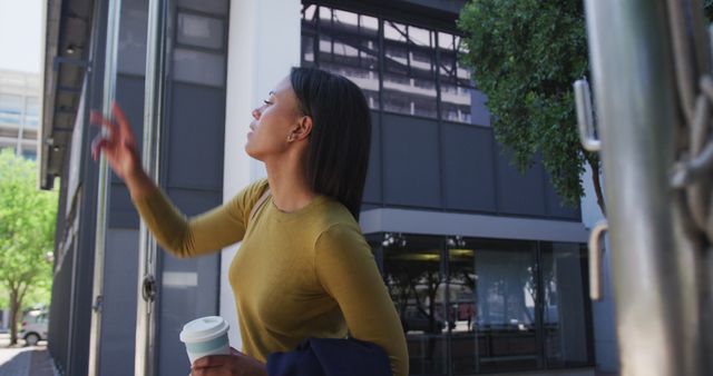 Woman Holding Coffee Cup while Pointing Outdoors in Urban Area - Download Free Stock Images Pikwizard.com