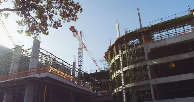 A construction site with a tower crane and scaffolding indicates ongoing development, with copy space. The image captures the essence of urban expansion and the construction industry's role in shaping cityscapes.