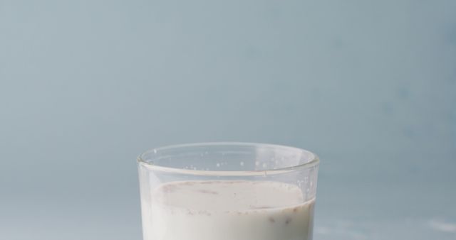 Glass of almond milk displaying almond bits floating, perfect for advertisements on plant-based beverages, health and wellness blogs, or recipes requiring dairy alternatives. Useful in articles promoting vegan lifestyles or nutritious diets.
