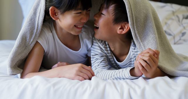 Happy Siblings Laughing Under Blanket on Bed - Download Free Stock Images Pikwizard.com