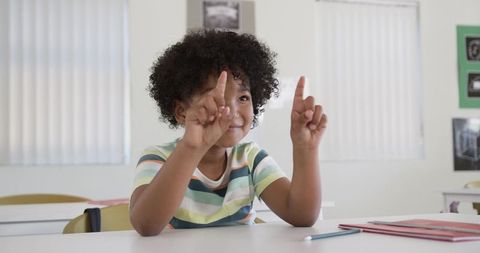 Curious student raising both index fingers in classroom showing engagement and confidence