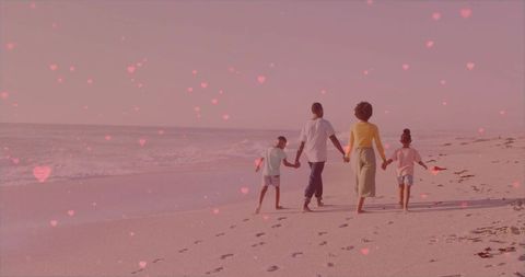 Family walking barefoot on beach at dusk leaving footprints with heart bokeh overlay
