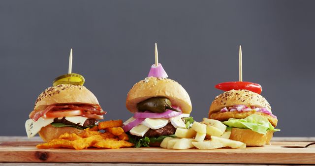Perfect for use in restaurant menus, food blogs, or culinary advertising. Showcases a variety of gourmet burgers with unique toppings and sides on a wooden board, highlighting rich textures and flavors.