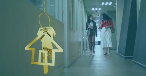 Golden Keys to Home Over Professionals Walking in Office