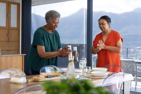 African american senior women seasoning bread at modern dining table with mountain view