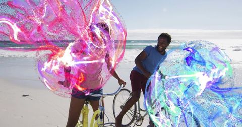 Laughing couple cycling on sunlit beach with neon particle ribbons creating vibrant motion