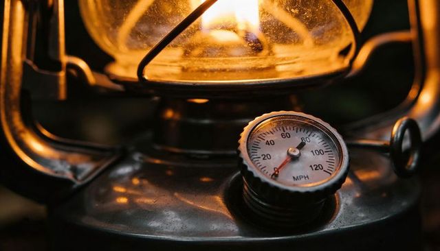 Glowing vintage kerosene lantern with glass globe, burning wick and mph gauge