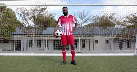 Confident Soccer Player Standing on Field with Ball