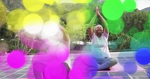 Senior women practicing rooftop yoga together raising hands for mindfulness and wellness
