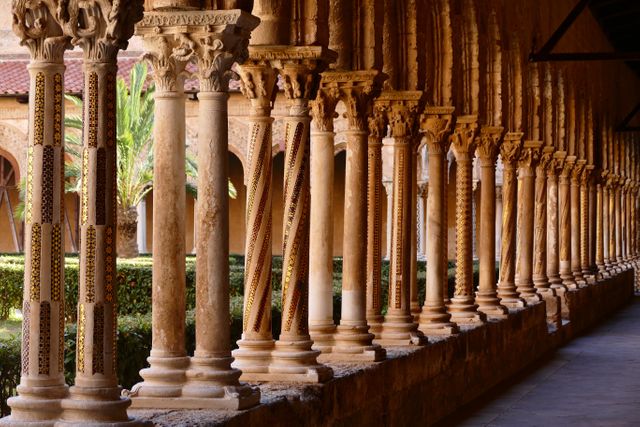 Stone columns with intricate carvings line the corridor of an ancient monastery garden. Useful for travel and tourism materials, educational purposes, history and architecture illustrations, and cultural heritage promotions.