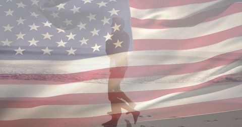 Walking silhouette on wet shoreline with faded american flag overlay, patriotic solitude