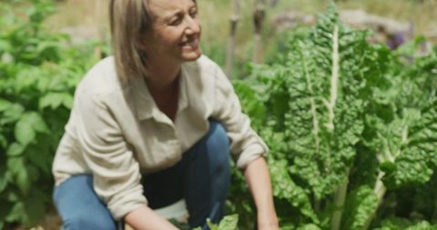 Smiling Woman Gardening in Lush Vegetable Garden