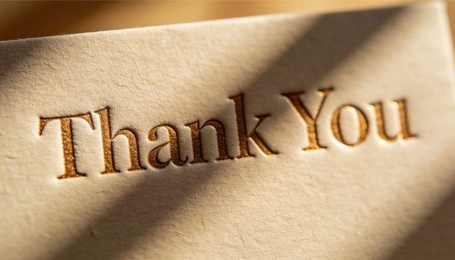 Embossed thank you in warm gold foil on cream textured cardstock with diagonal shadow