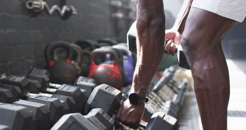 Man Selecting Dumbbells for Weightlifting in Gym with Focus on Fitness