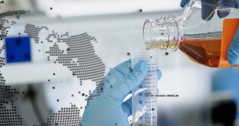 Gloved technician pouring amber reagent into graduated cylinder with global data overlay