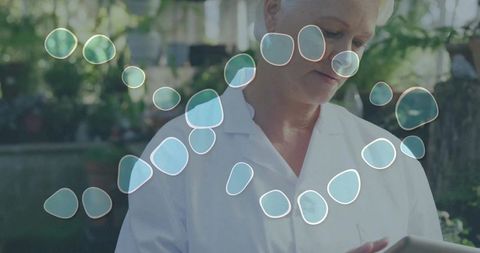Senior woman using tablet in bright sunlit garden patio