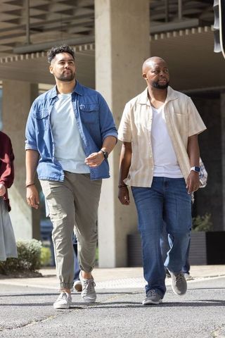 African american men walking together on urban sidewalk under slatted canopy