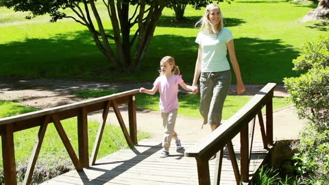 Mother and Daughter Strolling in Lush Park on Sunny Day